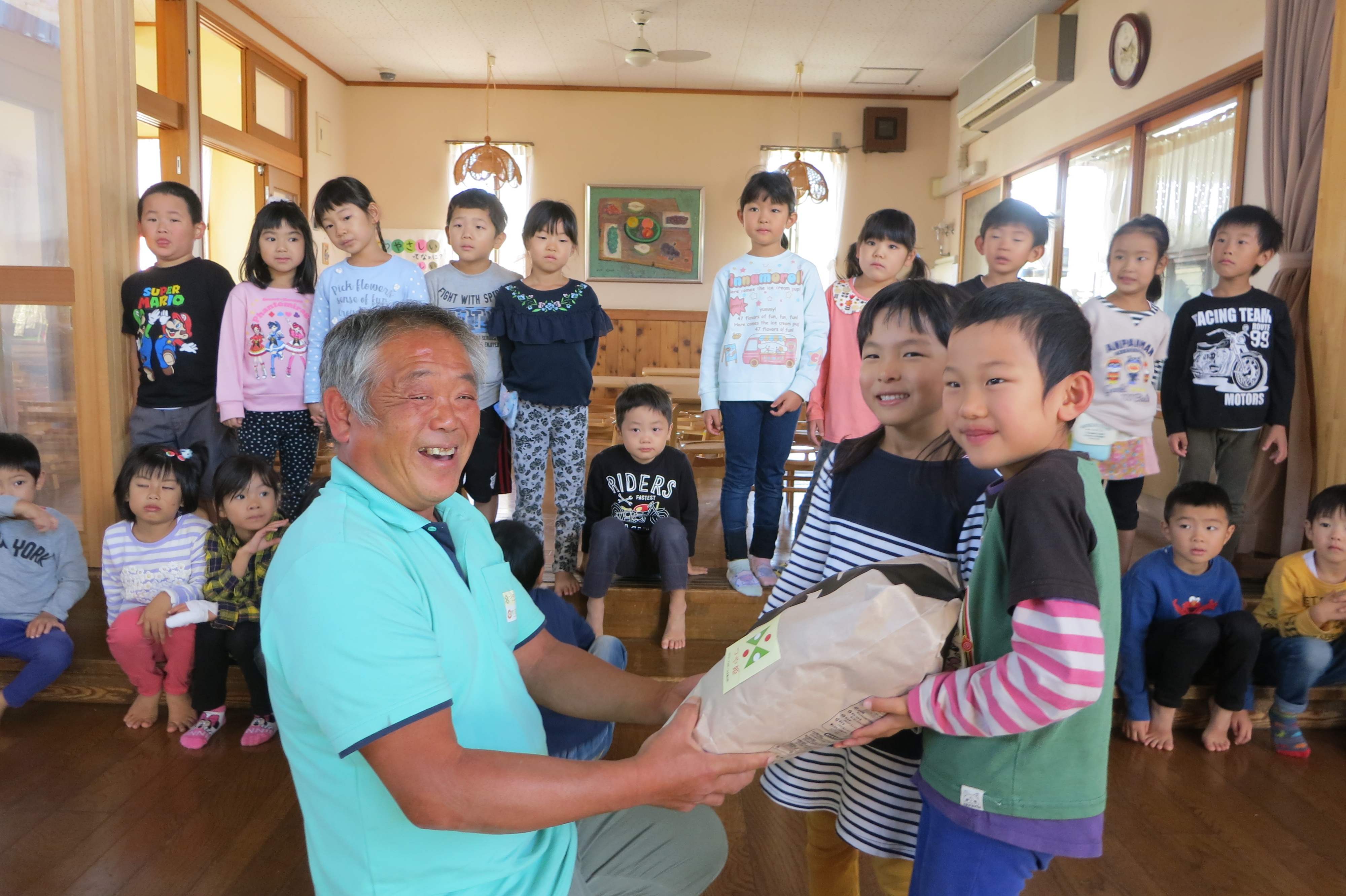 つや姫雪若丸を園児達に手渡す佐藤マイスター